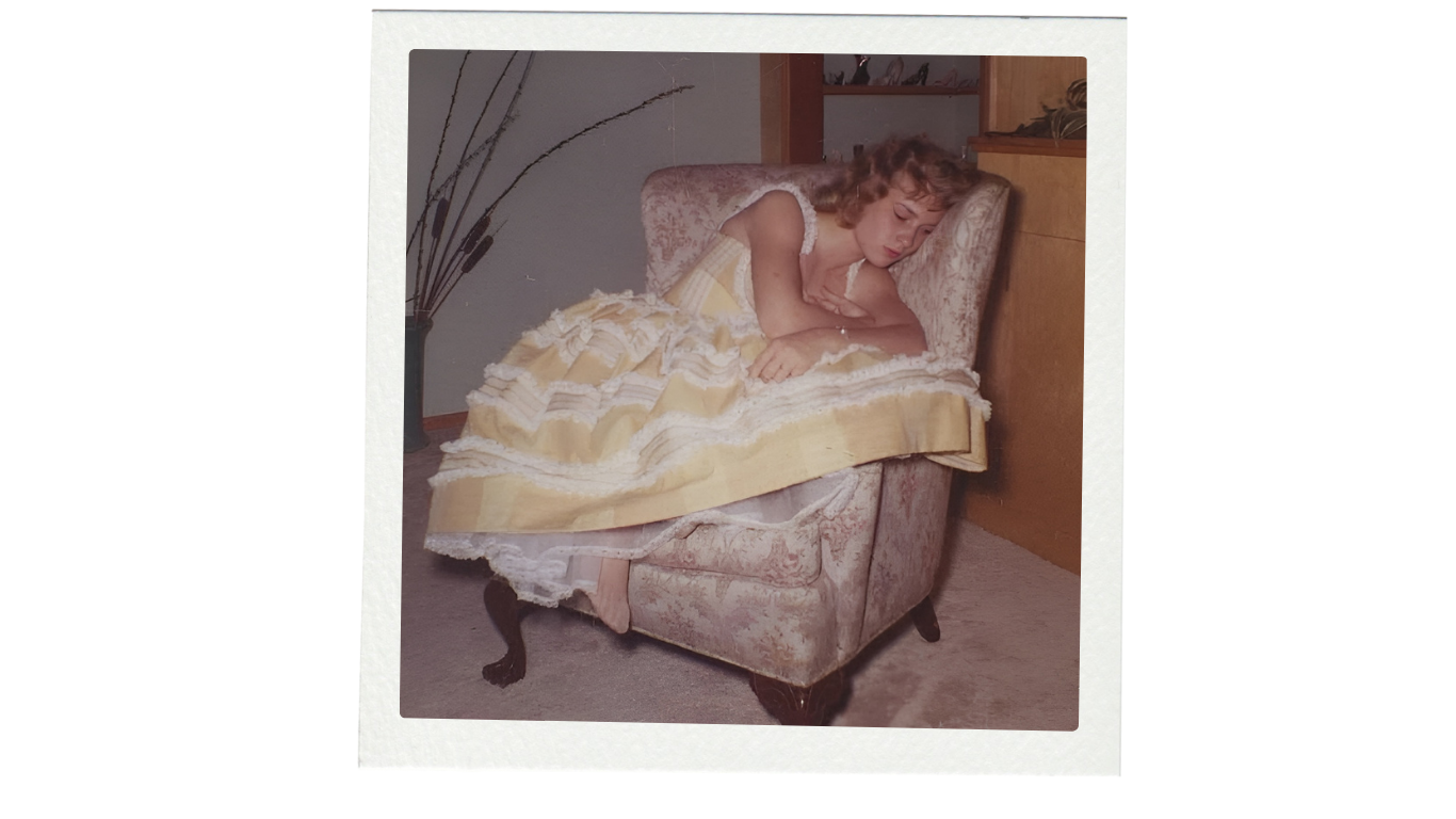 Woman in a yellow dress sitting on a patterned chair indoors.